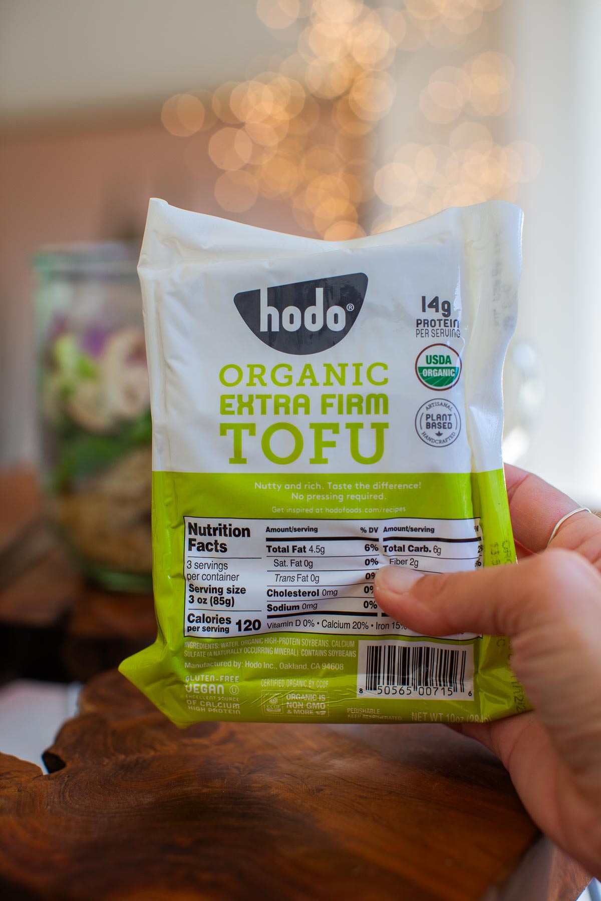 A hand holding a package of Hodo Organic Extra Firm Tofu.