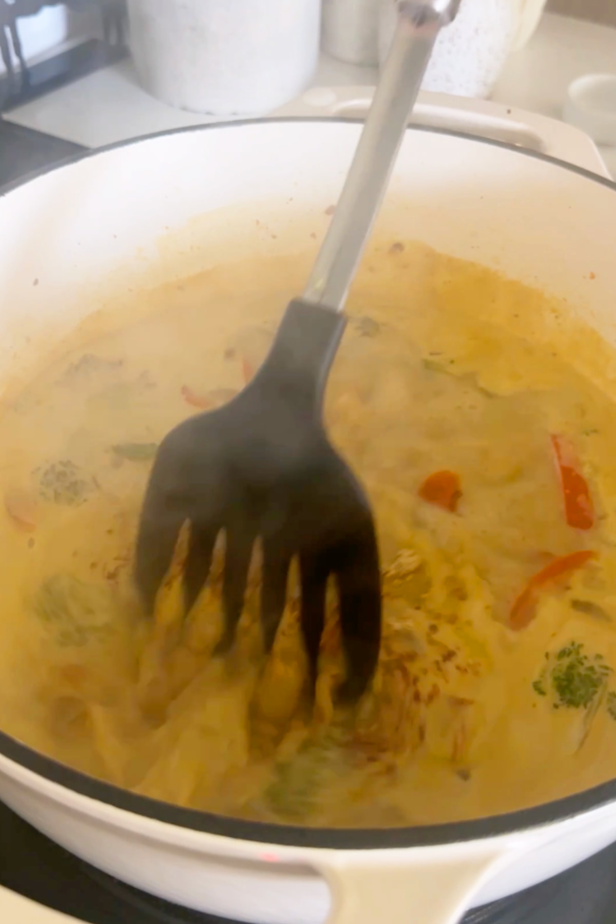 The simmering broth and vegetables for this glass noodle soup recipe in a large dutch oven pan.