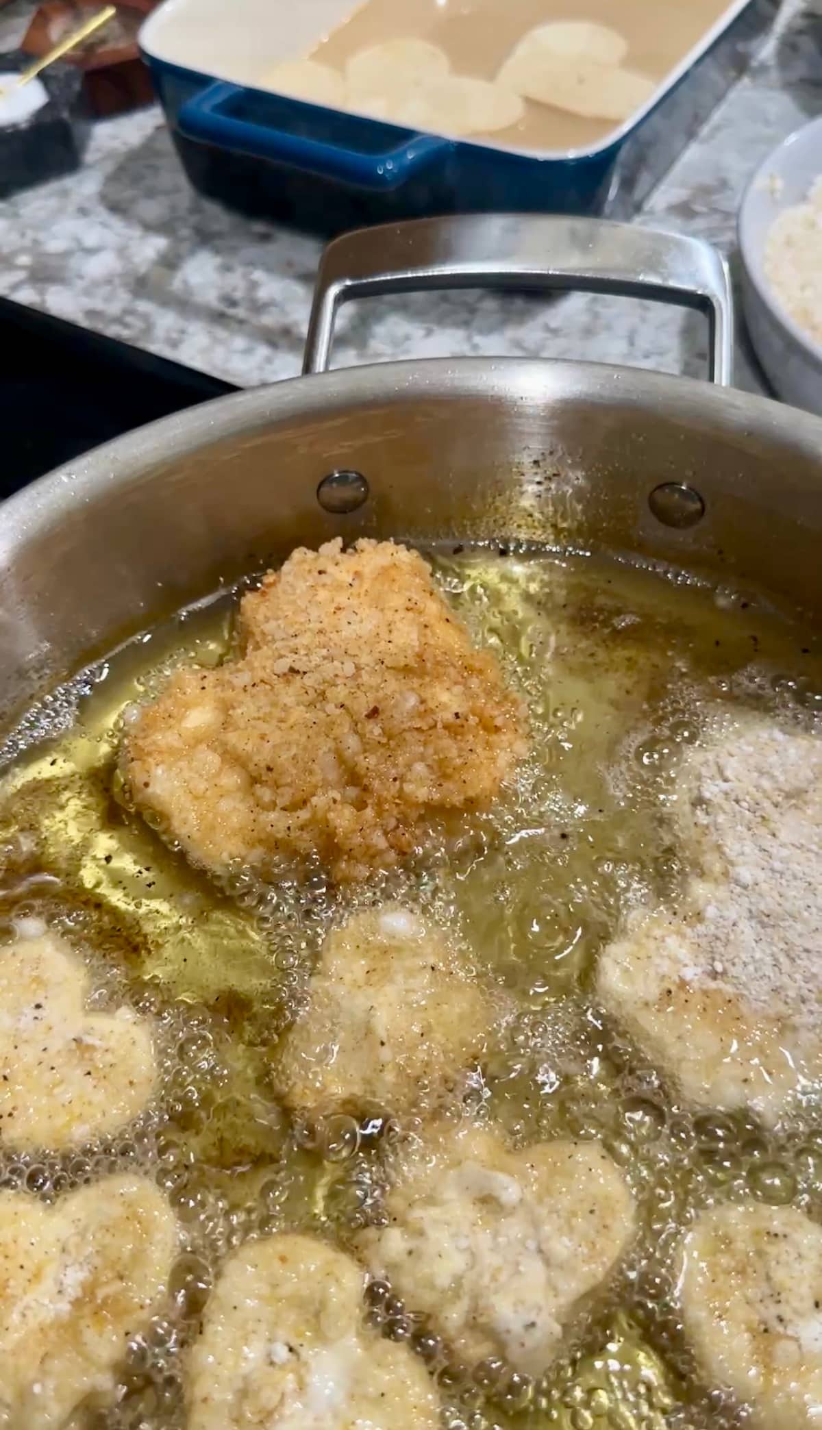 Chunks of crispy fried tofu hearts deep frying in a pan for a vegan fried chicken recipe.