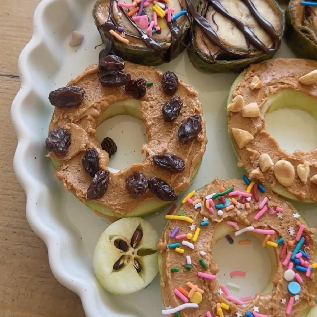 Fresh apple donuts with various toppings in a white serving dish.