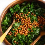 Massaged kale salad with a lemon garlic dressing topped with roasted chickpeas in a wooden serving bowl.