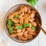 Dairy-free pink sauce pasta in a bowl and garnished with fresh basil.