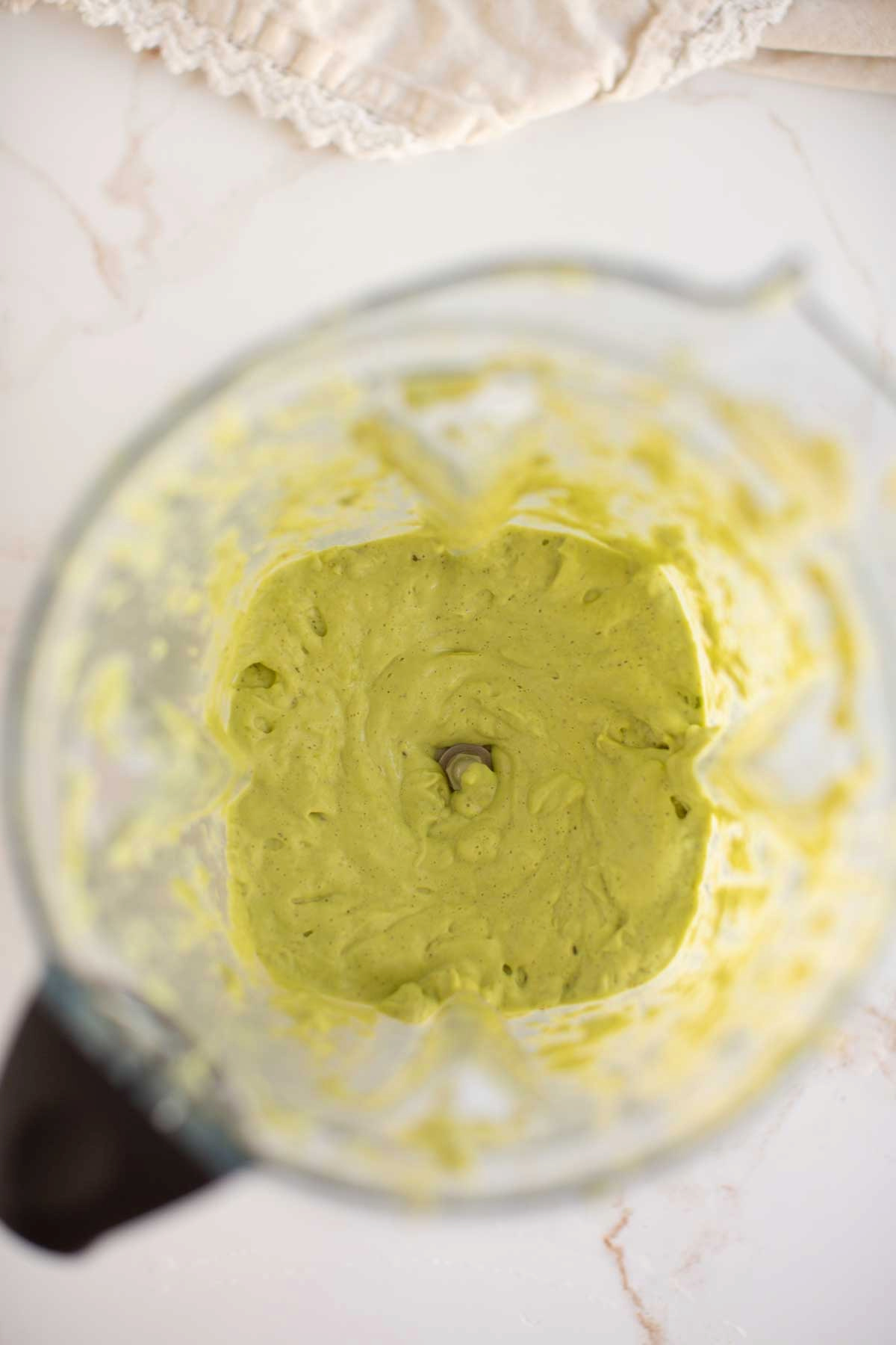 Homemade, dairy-free avocado ranch dressing being mixed in a blender.