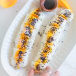 Mango sticky rice sushi made with spring roll wrappers topped with black sesame seeds.