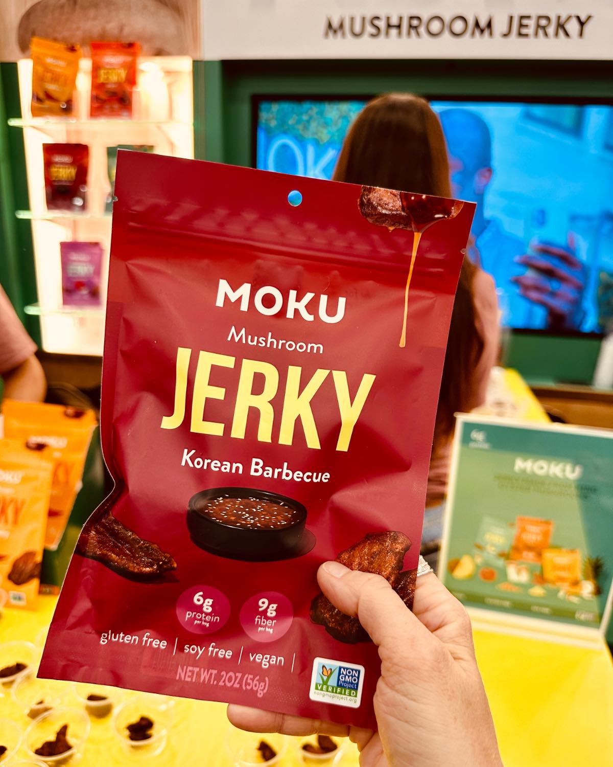 Holding a bag of Moku mushroom jerky in from of the booth at the Natural Products Expo West.