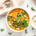 A best vegan stew recipe served in white bowls with plant based parmesan and silver spoons on the side.