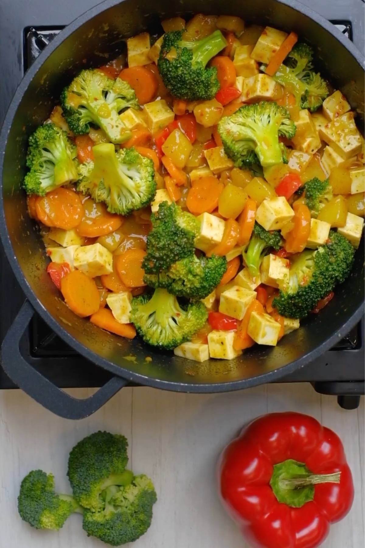 Broccoli added to yellow tofu curry recipe in a skillet.
