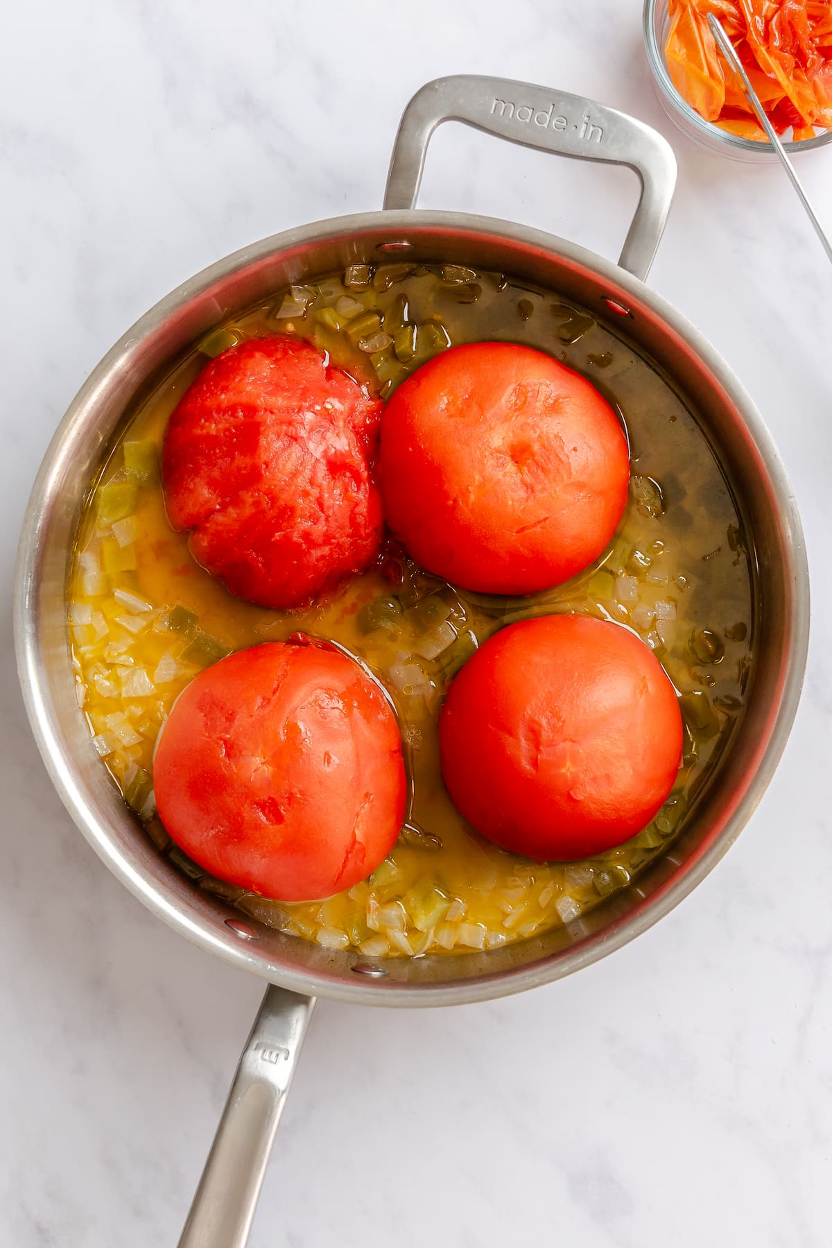 Skin removed from one whole tomato before crushing for a vegan shakshuka recipe.