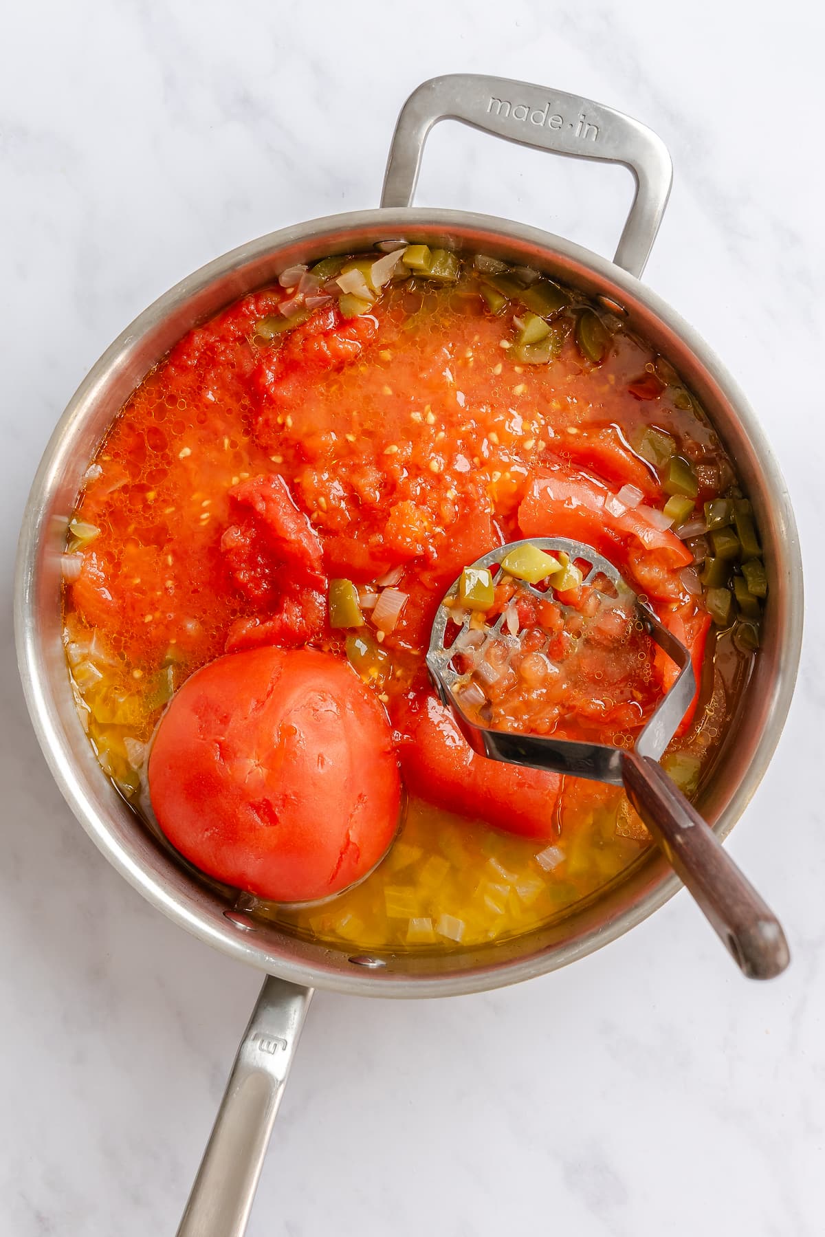Mashing tomato without skin to make a sauce for vegan shakshuka.