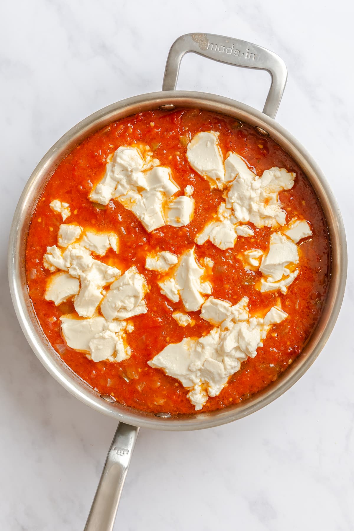 Pieces of silken tofu added to the tomato sauce of a vegan shakshuka dish.