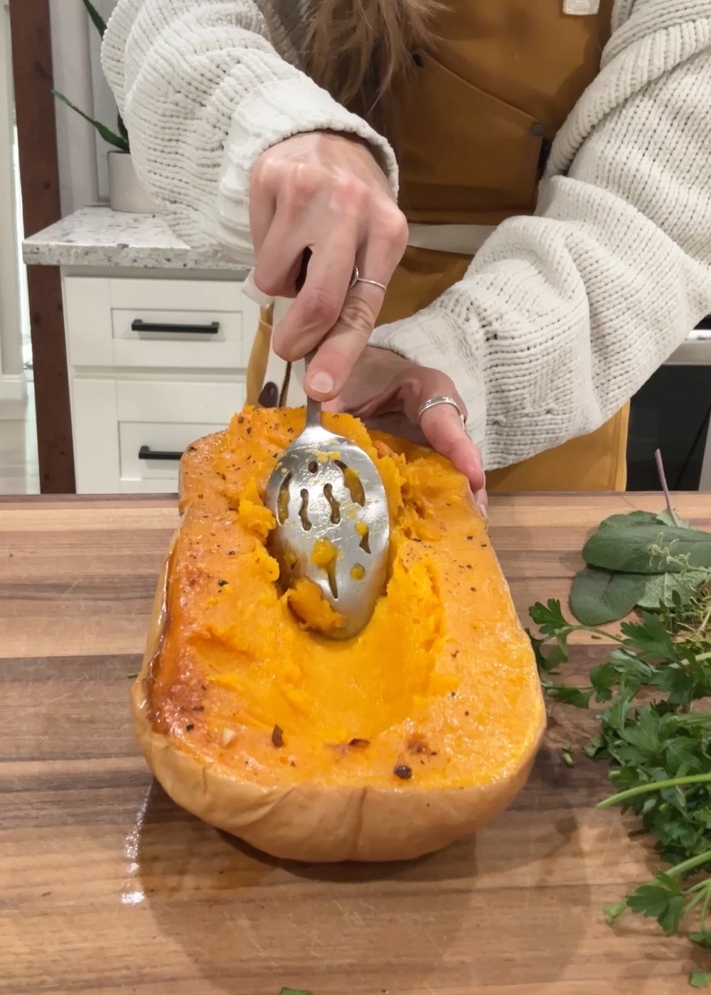 Michelle Cehn scooping a channel in a roasted butternut squash with a large spoon.