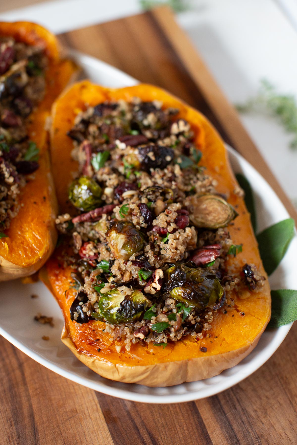 Two halves of stuffed butternut squash with quinoa on a white platter.
