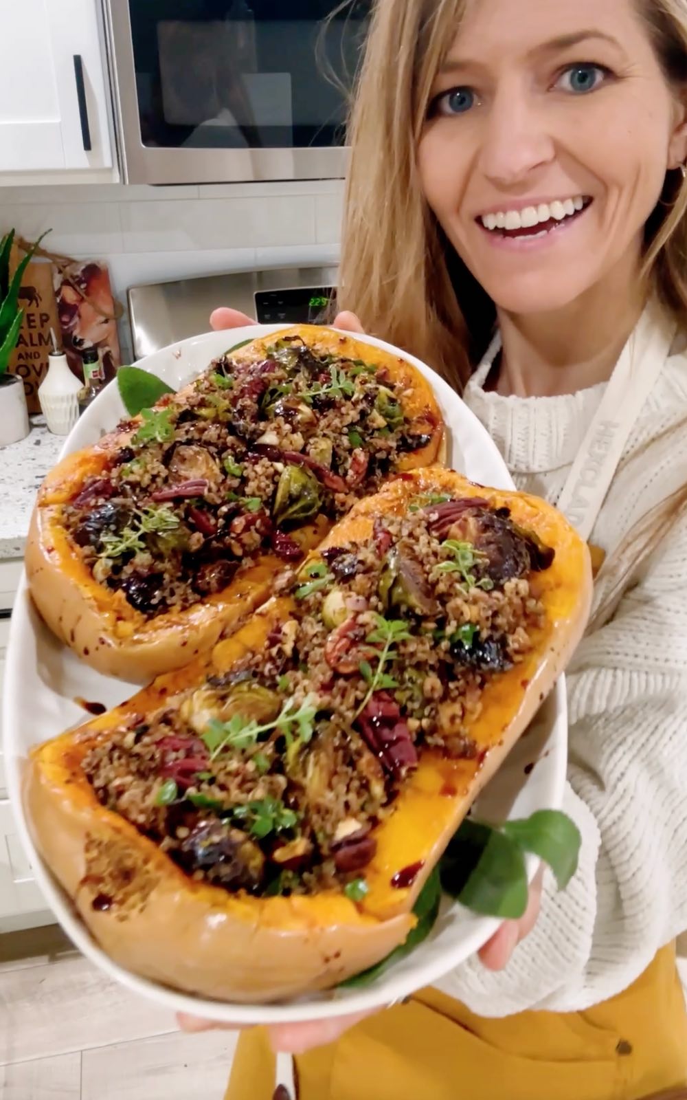 A stuffed butternut squash plated for Thanksgiving held out by vegan chef Michelle Cehn.