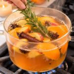 A glass pot with simmering festive fall smelling orange peels, cinnamon, rosemary, and pumpkin pie spice.